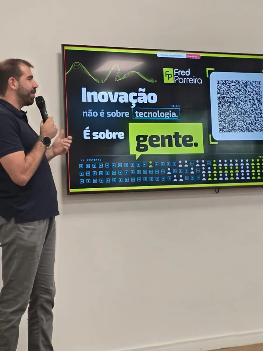 Fred Parreira apresentando, ao lado da tela com a frase: inovação não é sobre tecnologia, é sobre gente